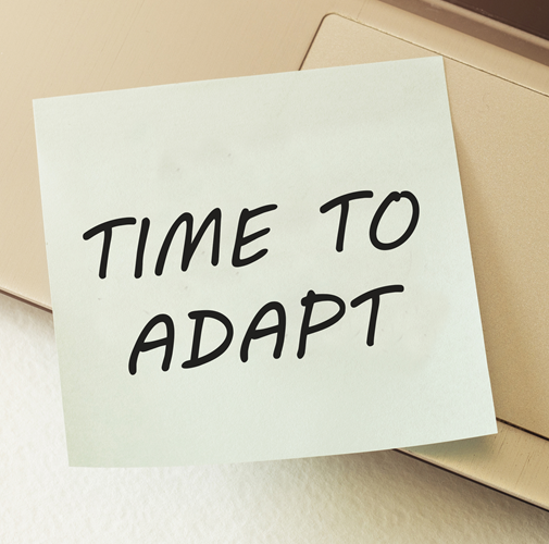 “Time to Adapt” written on a sticky note and placed on a laptop